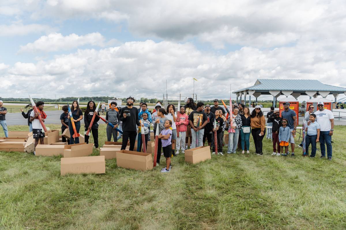 Group photo of bootcamp students and volunteers with their rockets at the launch field